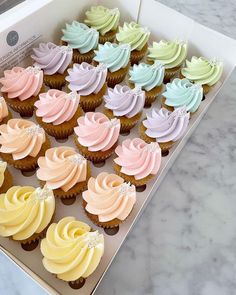 a box filled with cupcakes sitting on top of a marble counter next to a knife