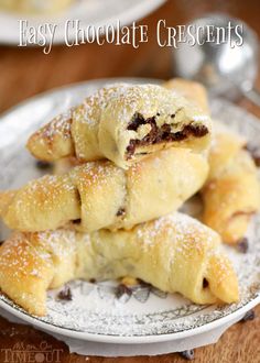 chocolate croissants stacked on top of each other on a plate with powdered sugar