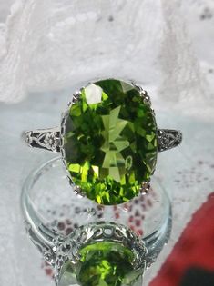 This filigree ring is an Edwardian antique reproduction in sterling silver set with a Natural Green Peridot gemstone solitaire. This gem has very good color and clarity; some small visible inclusions (Si1 clarity to VS). This full cut oval gem is 14mm x 10mm. This ring sits 7mm off the finger. The inside of the band is marked 925 for solid sterling silver. Notice the beautiful floral leaf design of the silver filigree setting and the etched band. Elegant Lime Green Jewelry With Center Stone, Classic Green Filigree Ring With Gemstone, Elegant Lime Green Rings For Formal Occasions, Elegant Lime Green Formal Ring, Elegant Formal Lime Green Ring, Elegant Green Filigree Ring With Gemstone, Green Sterling Silver Classic Filigree Ring, Classic Green Filigree Ring Hallmarked, Classic Green Sterling Silver Filigree Ring