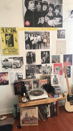 a record player sitting on top of a wooden table in front of a wall covered with posters