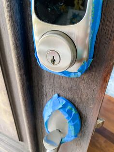 an electronic door lock on a wooden door with blue tissue paper around it and a plastic bag hanging from the handle