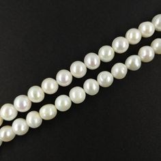 three strands of white pearls on a black surface with one strand missing the bead