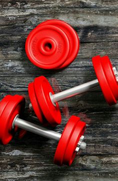 three red dumbbells on a wooden surface