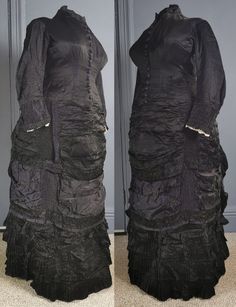 A superb, gothic Victorian antique bustle dress for mourning, dating to the early 1880s / natural form era - excellent condition, and a rare larger size. One piece, in a glossy two tone silk, black, the reverse in purple, the dress reflecting subtle purple tones. Closely fitted to the body, the bodice boned, fastening in the front with woven dome buttons in purple from neck to hip. Small collar, and a small waist patch pocket. Long fitted sleeves, with gathered cuffs and lace trim on the inner e Black Victorian Gothic Dress With Historical Design, Black Gothic Victorian Dress With Historical Design, Black Victorian Dress With Long Sleeves, Black Long Sleeve Victorian Dress, Fitted Historical Victorian Dress For Larp, Fitted Victorian Dress For Larp, Black Historical Victorian Costume Dress, Historical Black Victorian Costume Dress, Black Victorian Dress With Ruffles