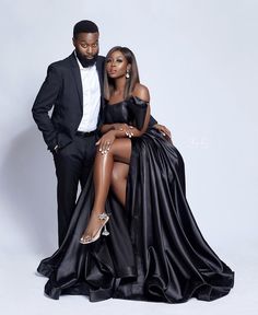 a man and woman in formal wear posing for the camera, one is wearing a black dress