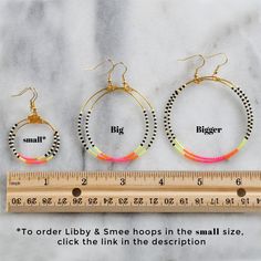 three pairs of hoop earrings sitting next to a measuring ruler on a marble countertop