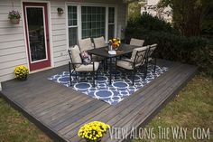 a backyard deck with chairs and table on it