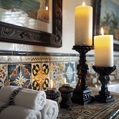 towels and candles sit on a table in front of an ornately decorated wallpaper