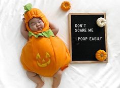 a baby in a pumpkin costume next to a sign that says don't scare me i poop easily