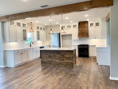 an empty kitchen with wood floors and white cabinets