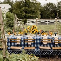 a table set up with sunflowers and blue checkered cloth for a party