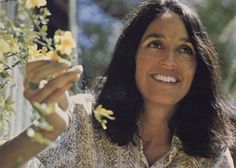 a woman is smiling and holding flowers in her hand