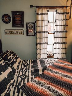 a bed sitting in a bedroom next to a window with pictures on the wall above it