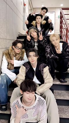 group of young men sitting on steps with one giving the peace sign and two pointing fingers up