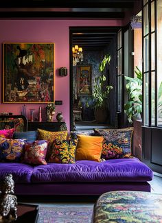 a living room filled with lots of furniture and colorful pillows on top of purple couches