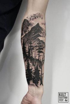 a man's arm with trees and mountains on it