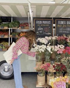 a woman standing in front of a flower shop