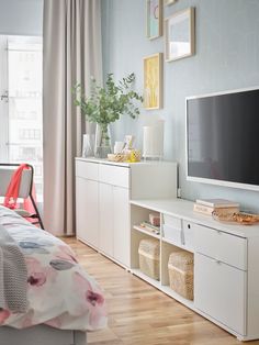 a bedroom with white furniture and a flat screen tv on top of the entertainment center