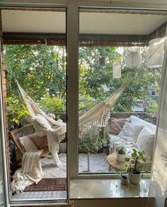 an open window with a hammock hanging from it's side and potted plants on the other side