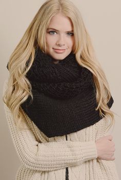 a woman with long blonde hair wearing a white sweater and black knitted scarf over her shoulders