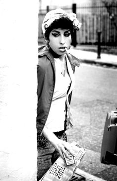 black and white photograph of woman leaning on pole