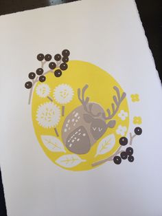 a paper with an image of a deer and berries on the bottom, in front of a yellow circle