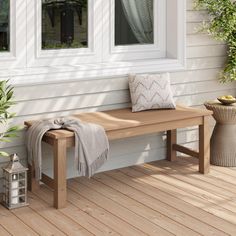 a wooden bench sitting on top of a wooden floor next to a white house with windows