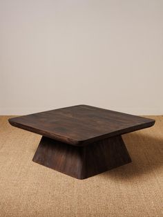 a square wooden table sitting on top of a rug