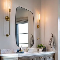 a bathroom vanity with a large mirror and two lights on the wall next to it