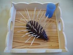 a wooden box with some toothpicks in it and a blue cup on the side