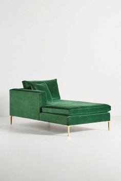 a green chaise lounge chair sitting on top of a white floor