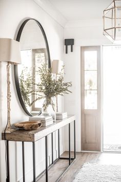 a console table with a mirror, lamp and vase on it in front of a door