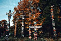 several totem poles in the woods with trees around them