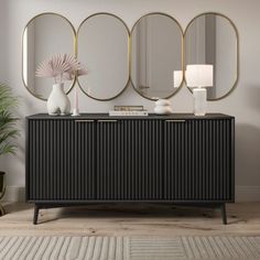 a black and gold sideboard with three round mirrors on the wall next to it