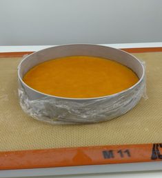 a metal bowl filled with soup on top of a mat covered in plastic wrappers