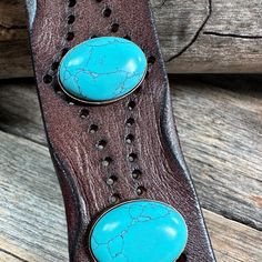 Brown leather bracelet that has a pattern of dots. It is adorned with turquoise Cabochon conchos. Measures 7.75" to 8.25" with two snaps for adjustment. Western Style Turquoise Leather Bracelets, Western Style Turquoise Bracelet, Hand Tooled, Turquoise Leather Concho Bracelets, Western Turquoise Bracelets With Concho, Western Style Turquoise Bracelet With Concho, Western Turquoise Bracelet With Concho, Adjustable Turquoise Western Bracelet, Adjustable Turquoise Cuff Bracelet With Concho, Adjustable Turquoise Leather Bracelet With Concho