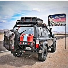 an suv with luggage strapped to the back is parked on the side of the road