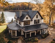 an aerial view of a house with a lake in the background and trees around it