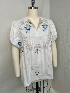 a white shirt with blue flowers on it is sitting on a mannequin head