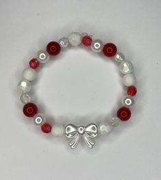 A red and white bow bracelet Cheap Beaded Bracelets For Christmas, Red Aesthetic Bracelet, White And Red Bracelets, Christmas Jewelry Aesthetic, Red And White Beaded Bracelet, White Jewelry With Bow For Gifts, White Bow Tie Jewelry As Gift, White Bow Tie Jewelry For Gift, White Jewelry With Decorative Bow For Party