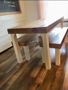 a wooden table and bench sitting on top of a hard wood floor next to a window