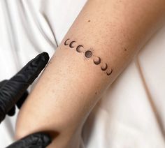 a woman's arm with three phases of the moon tattooed on it