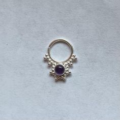 a ring with an amethorate stone in the middle on a white background