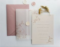 the wedding stationery is laid out on top of each other, including a pink envelope and wax stamp