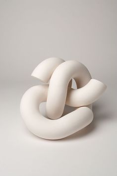 a white sculpture is sitting on the floor in front of a gray background and it looks like an interlocked object