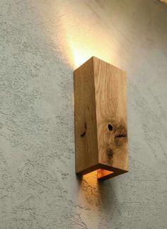 a wooden light fixture mounted on the side of a wall next to a concrete wall