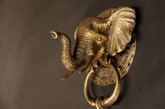 an elephant head mounted on the side of a door knocker, with its tusks curled up