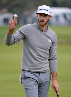 a man holding a golf ball in one hand and making the peace sign on the other