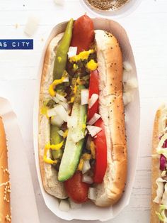 two hot dogs in buns with toppings and seasoning next to each other