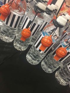 basketballs and water bottles are lined up on the table in front of each other